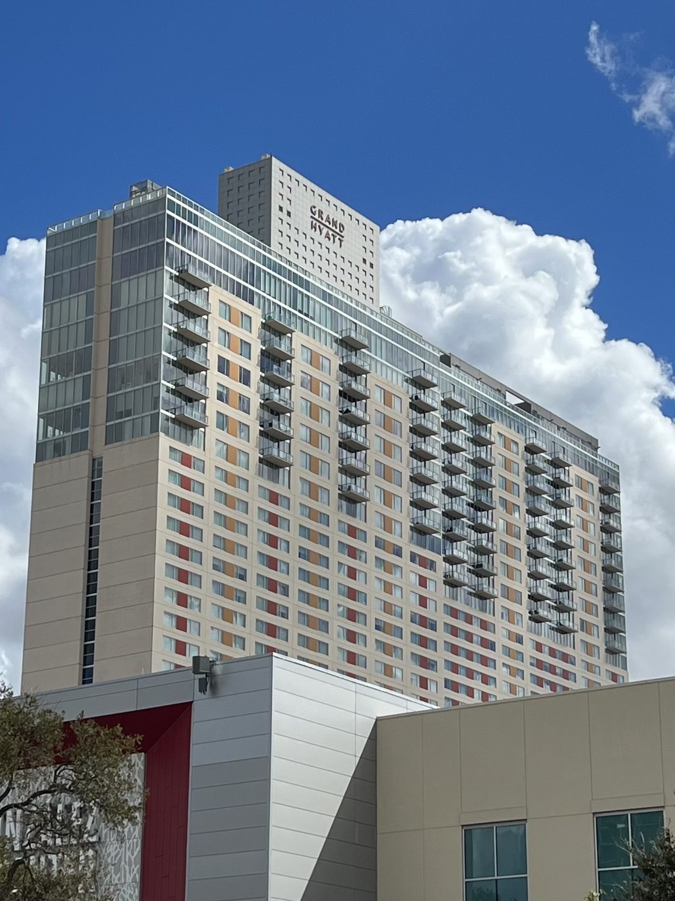 The Grand Hyatt San Antonio tower against a blue sky, with the convention centre in the foreground
